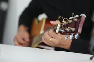 A person playing an acoustic guitar on a table photo