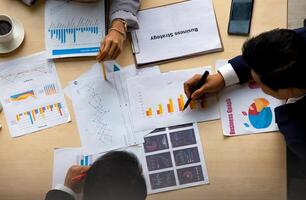 A group of people sitting around a table with papers and graphs photo