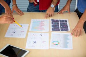 A group of people standing around a table with graphs and papers photo