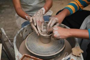 Two people are making pottery on a potter's wheel photo