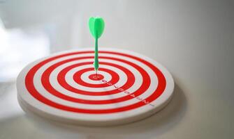 A dart is stuck in the center of a red and white target photo