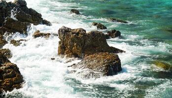 A view of the ocean from above with waves crashing on the rocks photo