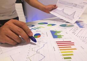 A person is holding a pen and looking at graphs photo