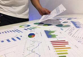 A man is looking at graphs and papers on a table photo