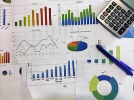 A calculator, pen and papers with graphs and charts photo