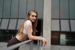 A woman in a white shirt and skirt leaning on a railing photo