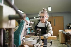 A woman in a workshop using a circular saw photo