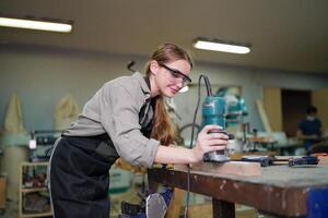 A woman in an apron is using a drill photo