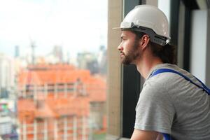A man in a hard hat looking out a window photo