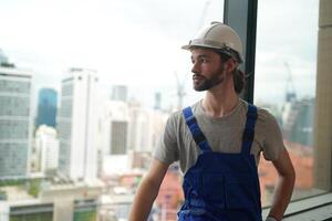 A man in overalls standing in front of a window photo