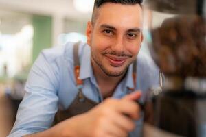 A man is smiling while standing in front of a coffee machine photo