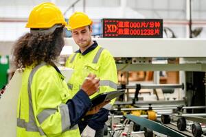 Two workers in hard hats standing in front of a machine photo