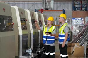 Two workers in safety vests standing next to a machine photo