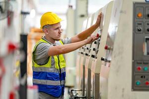 A man in a hard hat and vest working on a machine photo
