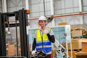 A man in a safety vest standing next to a forklift photo