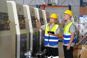 Two workers in safety vests standing next to a machine photo