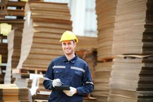 A smiling man in a hard hat standing in front of stacks of cardboard boxes photo