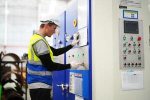 A man in a safety vest working on a machine photo