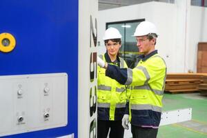 Two men in hard hats standing next to a machine photo