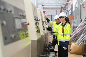 Two workers in safety gear working on a machine photo