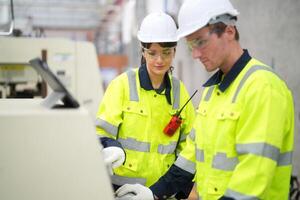 Two people in safety vests working on a machine photo