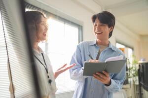A man and woman are talking while standing in front of a window photo