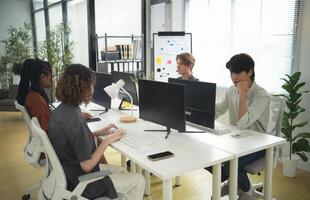 A group of people sitting at a table with computers photo