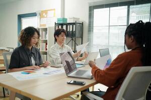 Three people sitting at a table with laptops photo