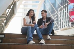 un Pareja sentado en pasos en frente de un edificio foto