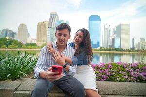 A man and woman are sitting on a bench in front of a city photo