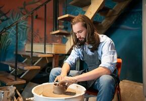 A man is making pottery on a pottery wheel photo