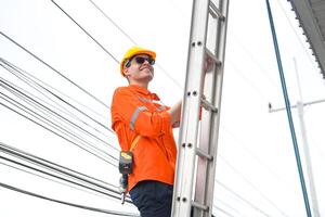 A man in an orange shirt is working on a ladder photo