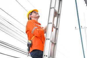A man in an orange shirt is standing on a ladder photo