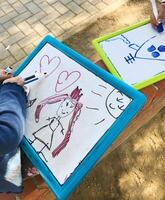 Hands of small student drawing on whiteboards photo