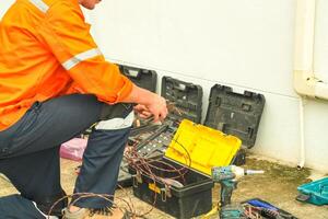 A man in an orange shirt and orange vest working on a toolbox photo