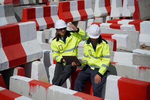 Two construction workers in hard hats sitting on a pile of red and white bricks photo