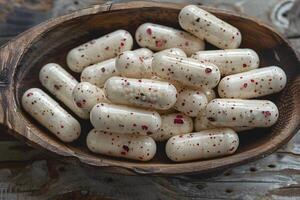 Herbal Medicine Capsules with Red and Black Specks in Wooden Bowl for Alternative Health Concepts photo