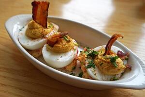 Close up seasoned boiled eggs served with crispy bacon bits photo