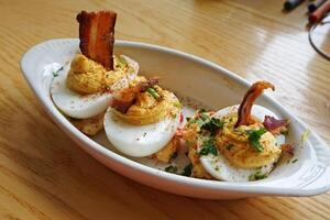 Close up seasoned boiled eggs served with crispy bacon bits photo