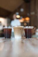 A glass of ice latte placed on the center between ice black coffee. photo