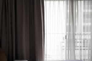 A soft gray curtains sunlit window with sheer curtains. photo