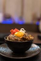 Roast Wagyu beef rice and raw egg bowl in a black bowl. photo