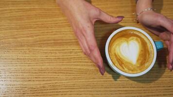 Cup of coffee close up. Coffee cup with art foam on wooden table video