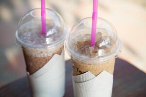 Two drinks with straws sitting on a table photo