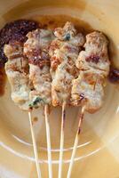 A plate with four skewers of meat on it photo