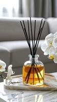A white table with a vase of flowers and a vase of reed diffuser photo