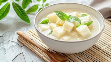A bowl of soup with some cubes of cheese photo