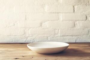 A simple white plate on a wooden table against a brick wall. photo