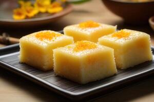 Four pieces of delicious square yellow cake on a dark gray square plate. photo