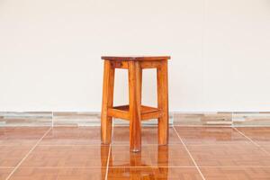 A wooden stool sitting on a tile floor photo